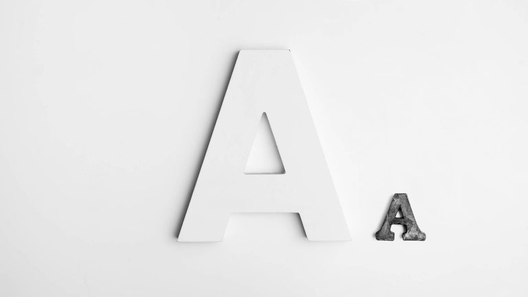 A large white letter A and a small, dark textured letter A sitting on a plain white background.