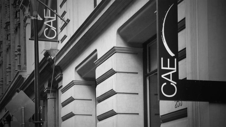 Black and white photo of "CAE" signs on the exterior of a classic-style building.