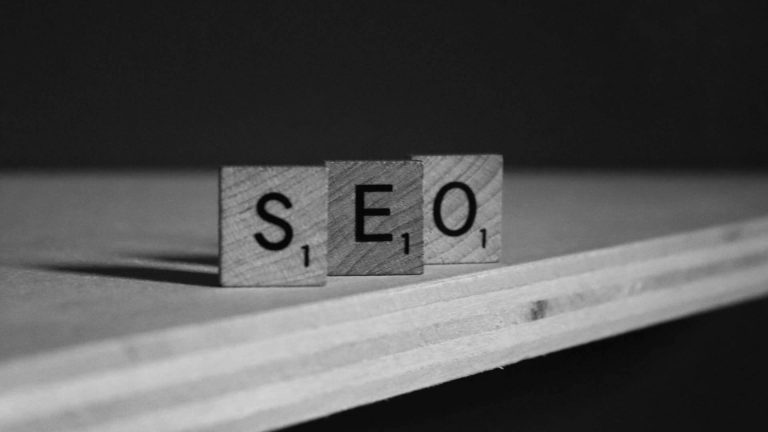 Black and white photo of wooden Scrabble tiles spelling out the acronym "SEO".