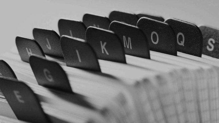Black and white close-up of the alphabetical divider tabs in a Rolodex card file.